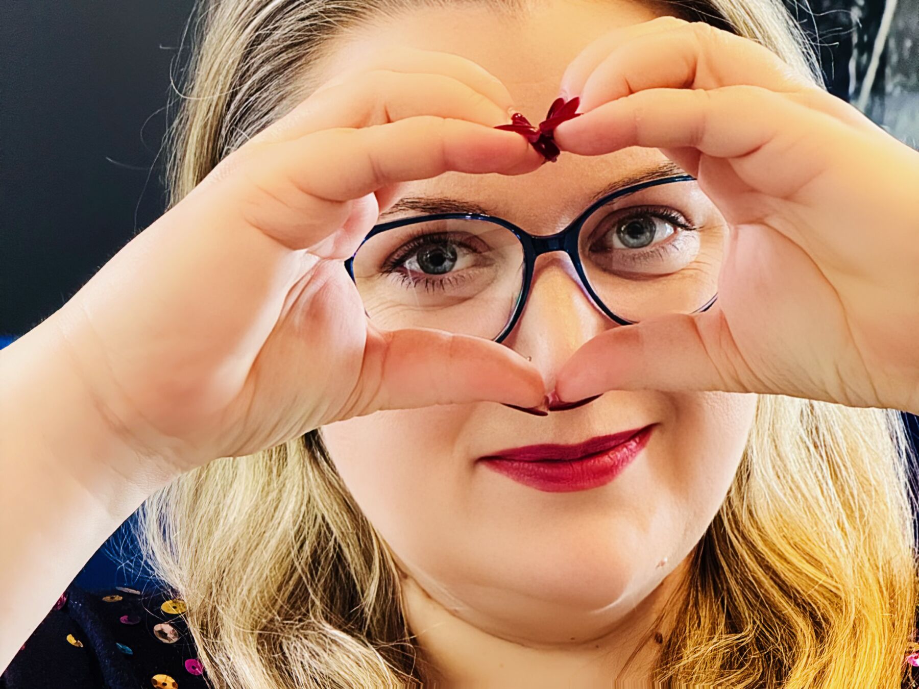 Kobieta w okularach, pokazuje palcami kształt serca, pokazuje miłość do okularów