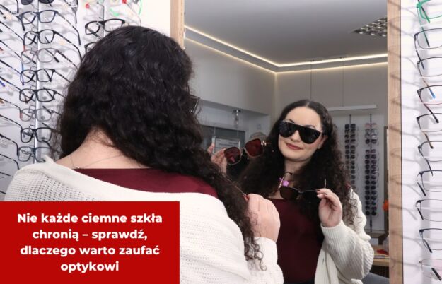 Nie każde ciemne szkła chronią – sprawdź, dlaczego warto zaufać optykowi Kobieta w salonie optycznym przymierza okulary przeciwsłoneczne przed lustrem. W tle ściana z oprawkami.